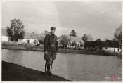 Krasocin 1944 r., żołnierz niemiecki pozuje do zdjęcia na tle współczesnej ulicy Wyzwolenia, przed sobą ma wejście na teren obozu pracy. 